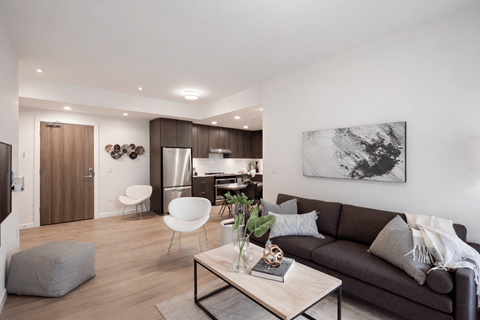 A modern living room with a grey couch, a coffee table, and a painting on the wall.