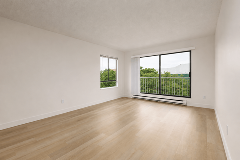Empty room with a window overlooking a green landscape.