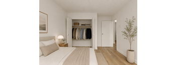 A bedroom with a large bed and a closet with clothes hanging.