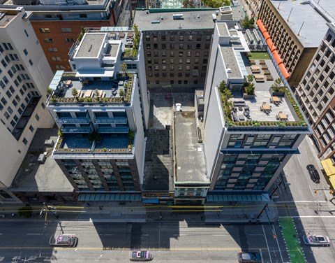 A tall building with a green roof is surrounded by other buildings.
