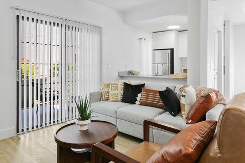 A living room with a couch, a coffee table, and a sliding glass door.