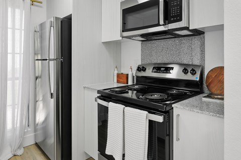 A modern kitchen with a black stove top oven and white cabinets.