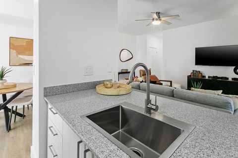 A modern kitchen with a granite countertop and stainless steel sink.