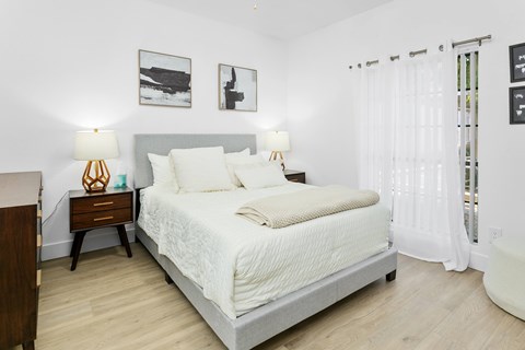 A bedroom with a bed, nightstands, and pictures on the wall.