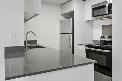A modern kitchen with a stainless steel refrigerator and a black oven.