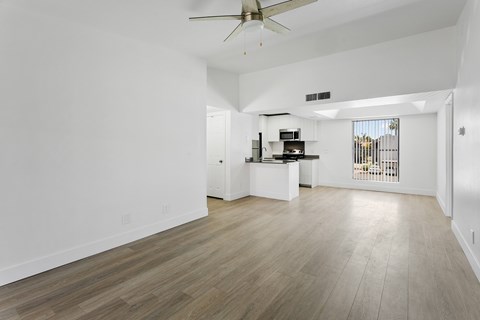 A spacious living room with a ceiling fan and lighting fixture.