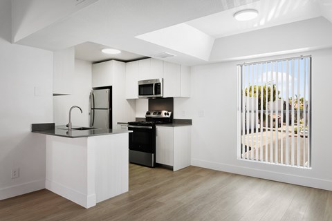 A modern kitchen with white cabinets and a black countertop.