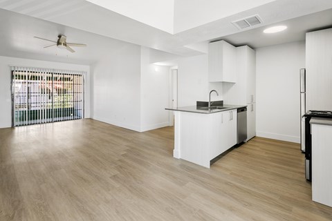 A kitchen with white cabinets and a wooden floor.