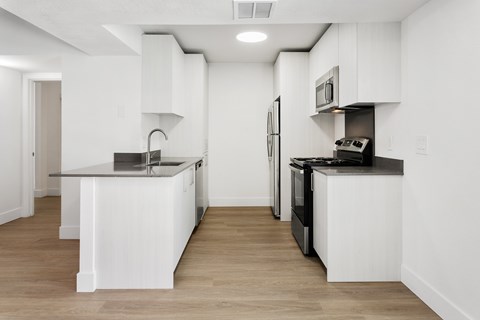 A modern kitchen with white cabinets and black appliances.