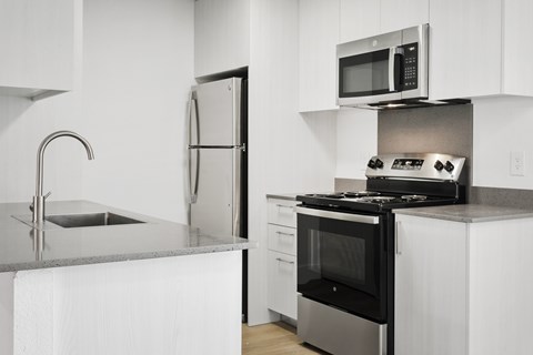 A modern kitchen with a stainless steel refrigerator and a microwave above the stove.