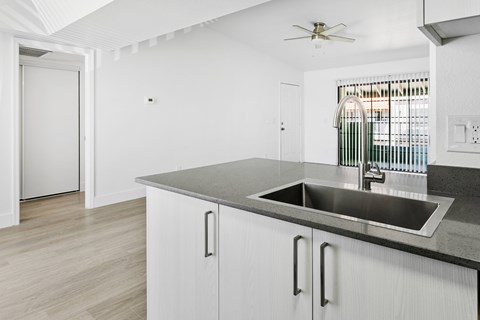 A modern kitchen with a sink and a ceiling fan.
