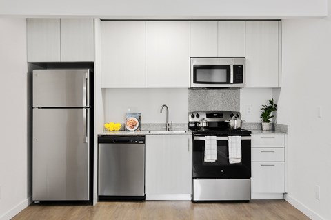 A modern kitchen with white cabinets and stainless steel appliances.