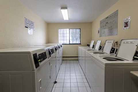 A laundromat with washers and dryers lined up.