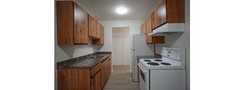 A kitchen with a white stove and wooden cabinets.