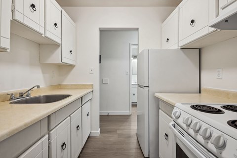 A kitchen with white cabinets and a white stove.