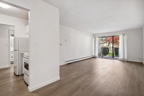 A spacious, empty room with wooden floors and white walls.