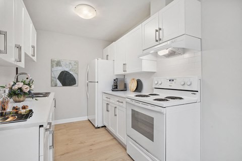 A white kitchen with a stove, refrigerator, and oven.