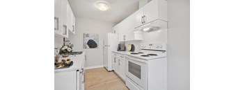 A white kitchen with a stove, refrigerator, and oven.