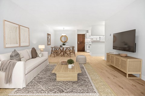 A living room with a white couch, a wooden coffee table, and a television.