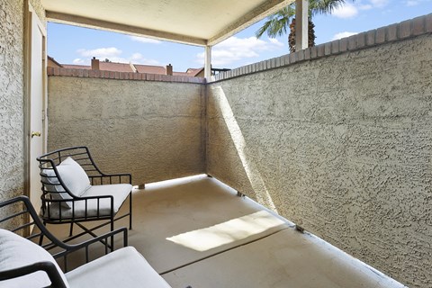 a balcony with chairs and a table and a wall with a palm tree