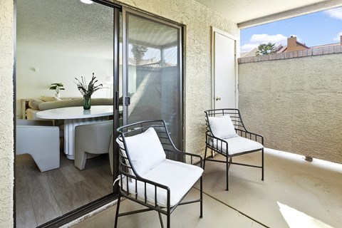 a small balcony with two chairs and a table