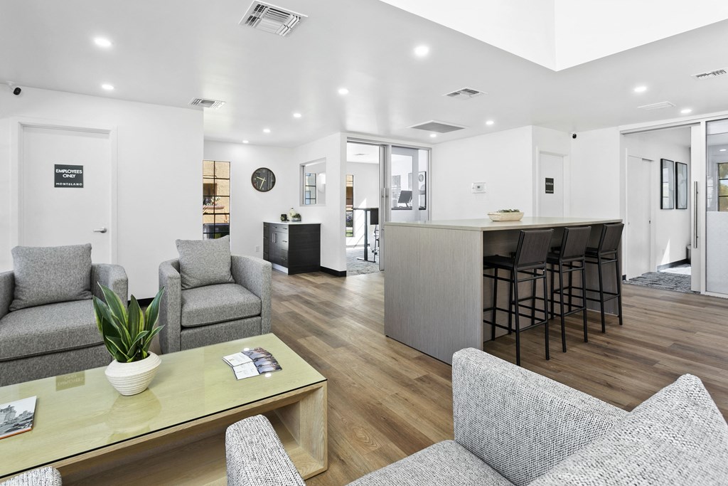 a living area with couches a coffee table and a kitchen in the background