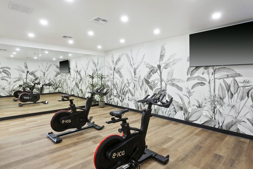 a row of exercise bikes in a room with a mural on the wall