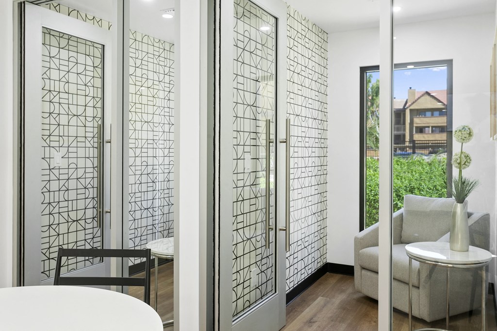 a white room with a white table and a white chair and a glass door with a view