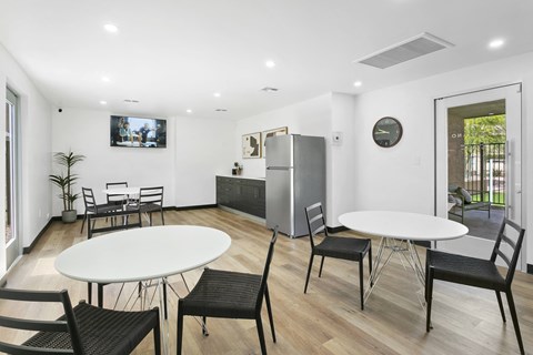 a room with two tables and chairs and a fridge in the corner of the room