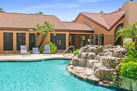 a swimming pool with a waterfall in front of a house