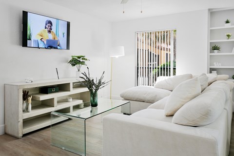 A modern living room with a white couch and a television mounted on the wall.