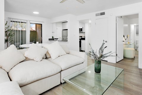 A modern living room with a white couch and a glass coffee table.