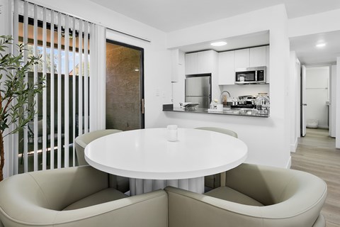 A modern kitchen with a white table and beige chairs.