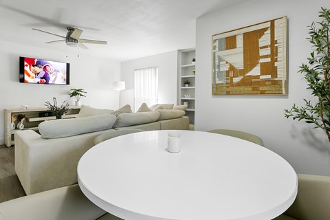 A living room with a white table and a television on the wall.