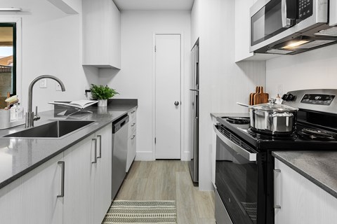 A modern kitchen with white cabinets and black countertops.