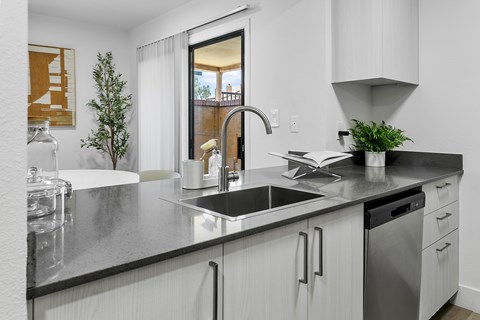 A modern kitchen with a black countertop and white cabinets.