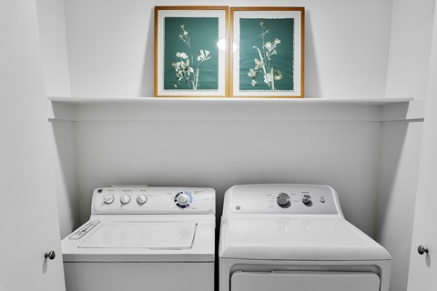 Two white front load washing machines in a laundry room.
