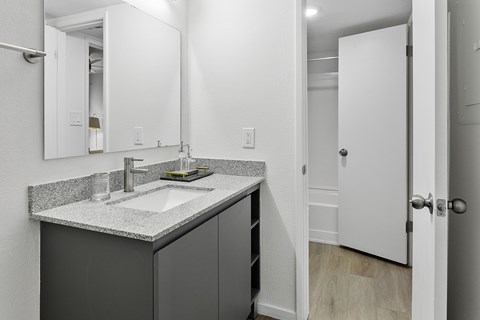 A bathroom with a sink, mirror, and cabinet.