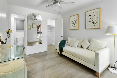 A living room with a white couch and a glass table.