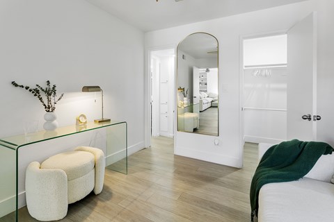 A white chair sits in front of a glass table with a plant on it.