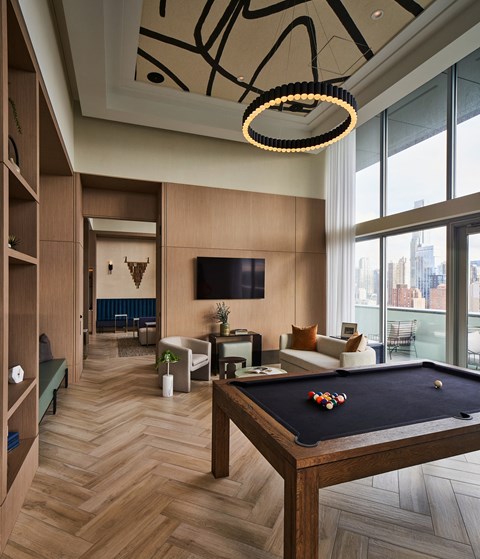 A pool table is in the middle of a room with a TV and a couch.
