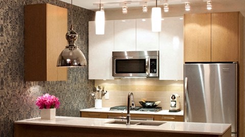 A modern kitchen with a stainless steel refrigerator and a microwave above the stove.