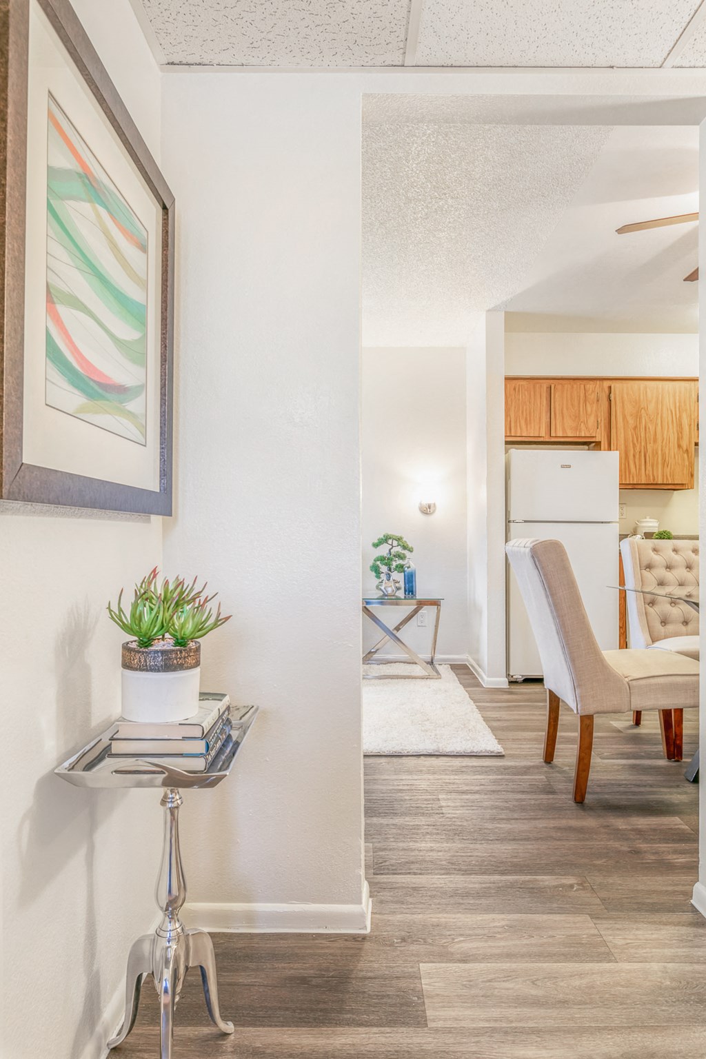 a living room and dining room with a white refrigerator and a table with a plant
