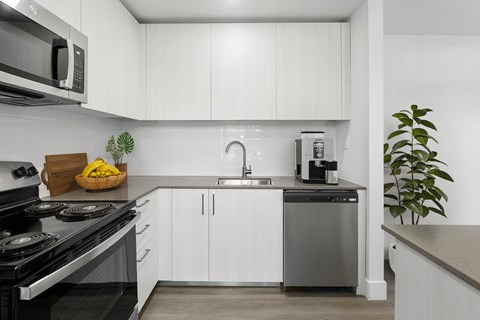 A modern kitchen with white cabinets and a black stove top.