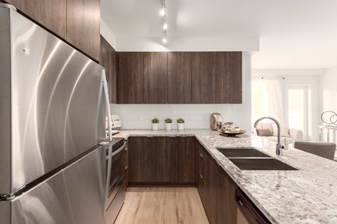 A modern kitchen with a stainless steel refrigerator and wooden cabinets.