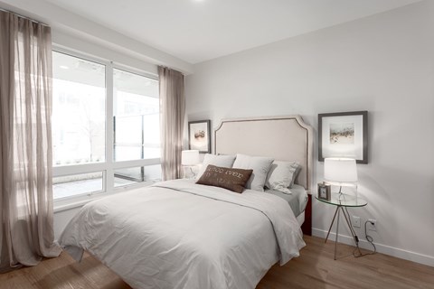 A bedroom with a large bed and a window with curtains.