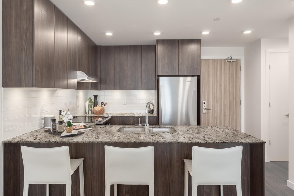 a kitchen with a granite counter top and a stainless steel refrigerator
