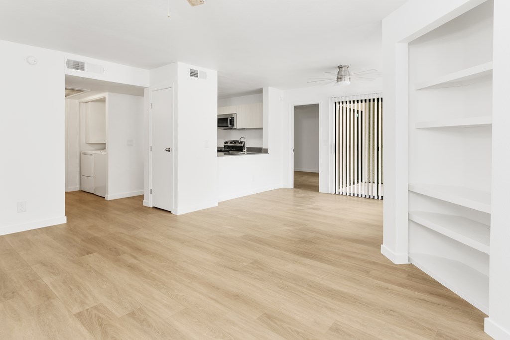 A white room with wooden flooring and a white door.