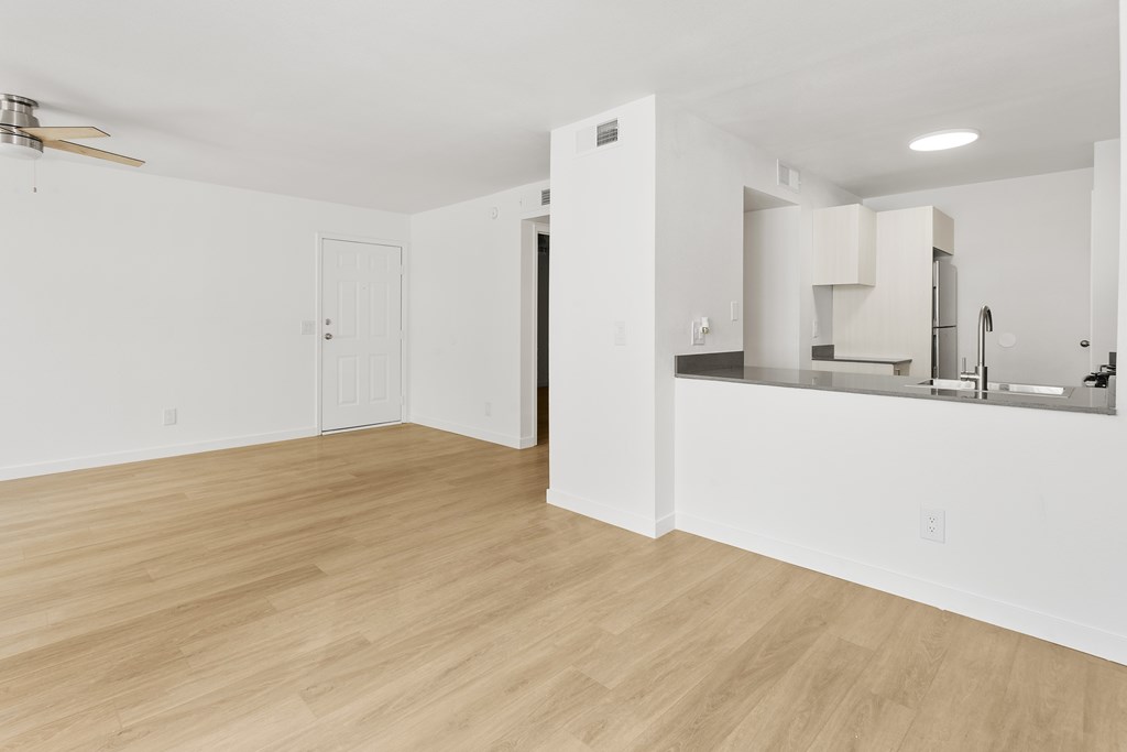 A room with a kitchen area and a wooden floor.