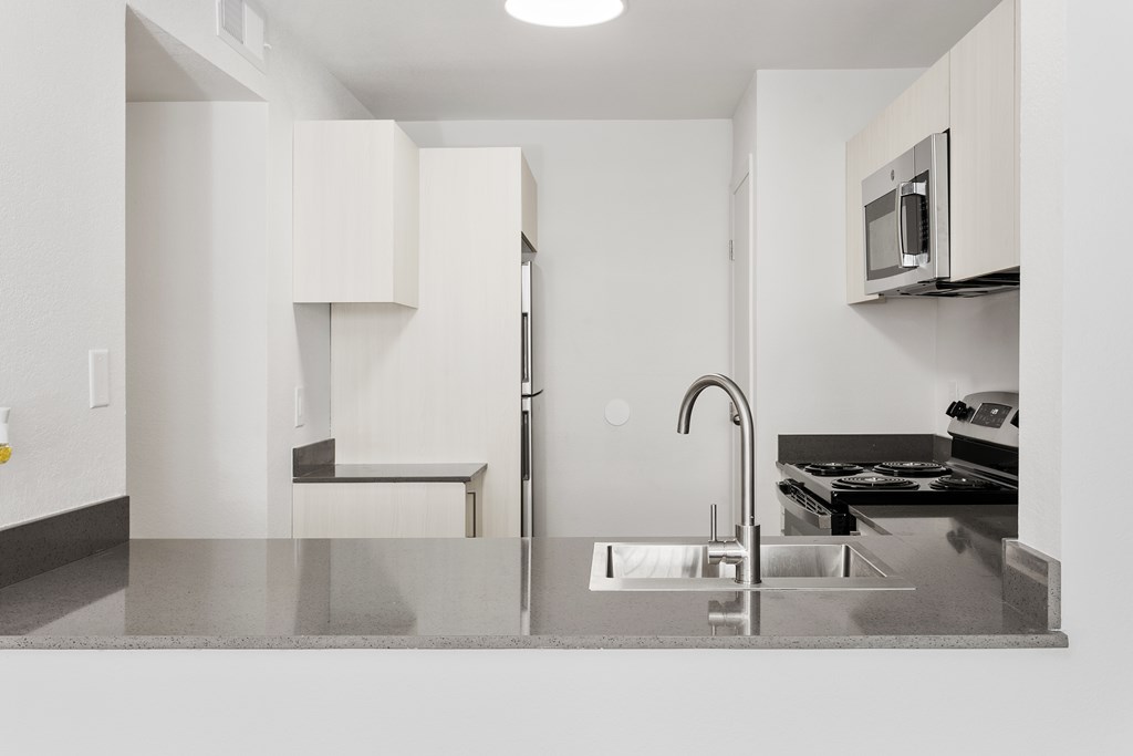 A kitchen with a sink, stove, and refrigerator.